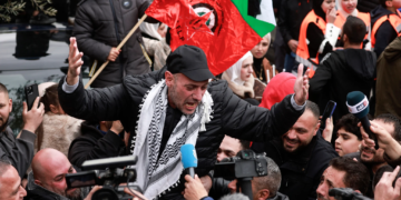 Группа палестинцев в ходе демонстрации; протестующие машут флагами и скандируют лозунги